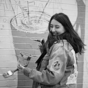 Melanie Coyne, Jr. Designer at CooperKatz, paints a mural for FIT